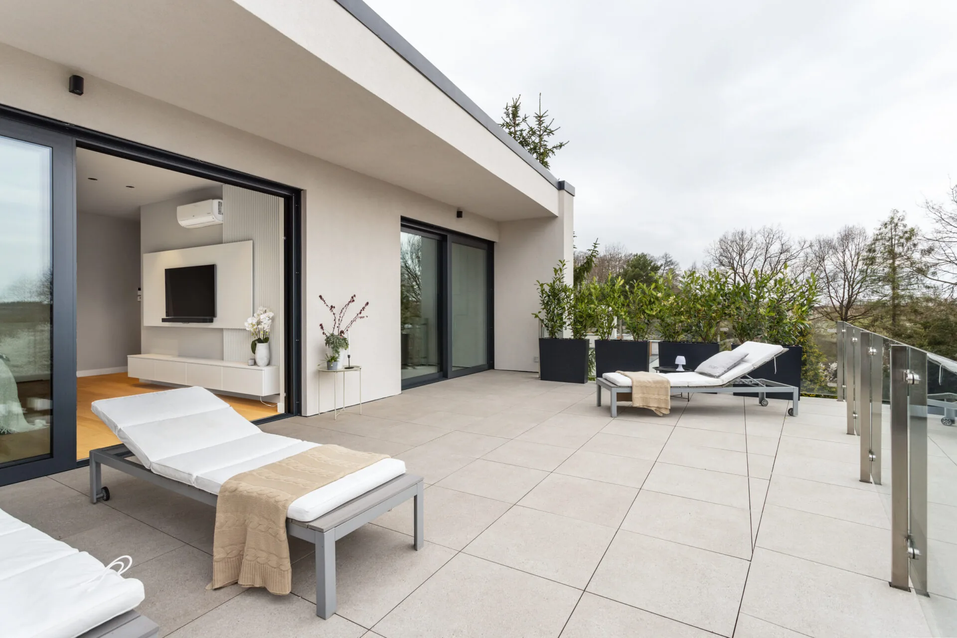 Dachterrasse mit Liegen, großformatigen Platten und Glasbrüstung