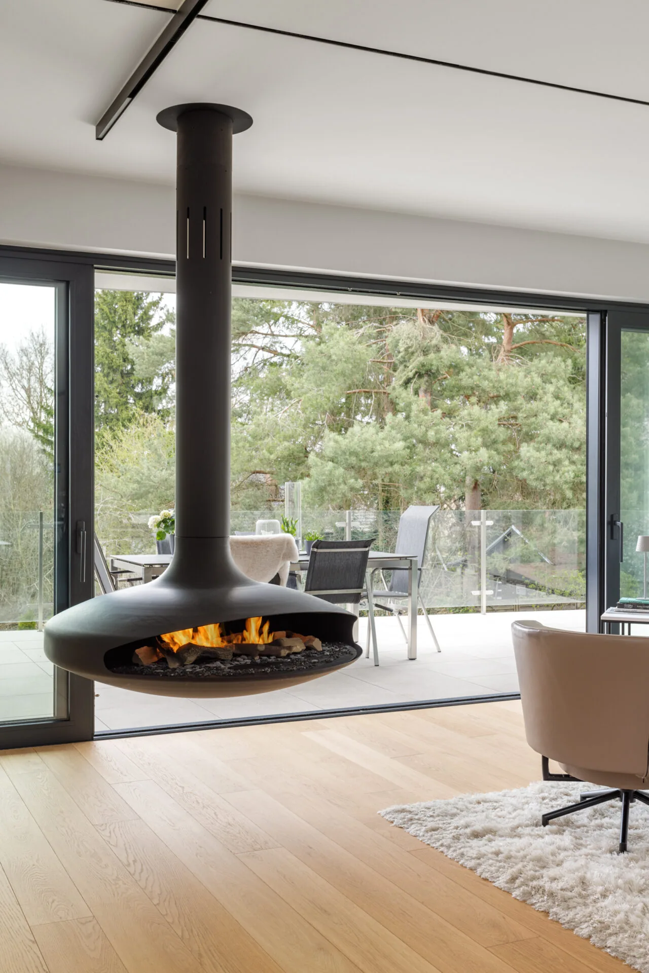 Hängender Kamin vor der Glasfront mit Blick auf die Terrasse
